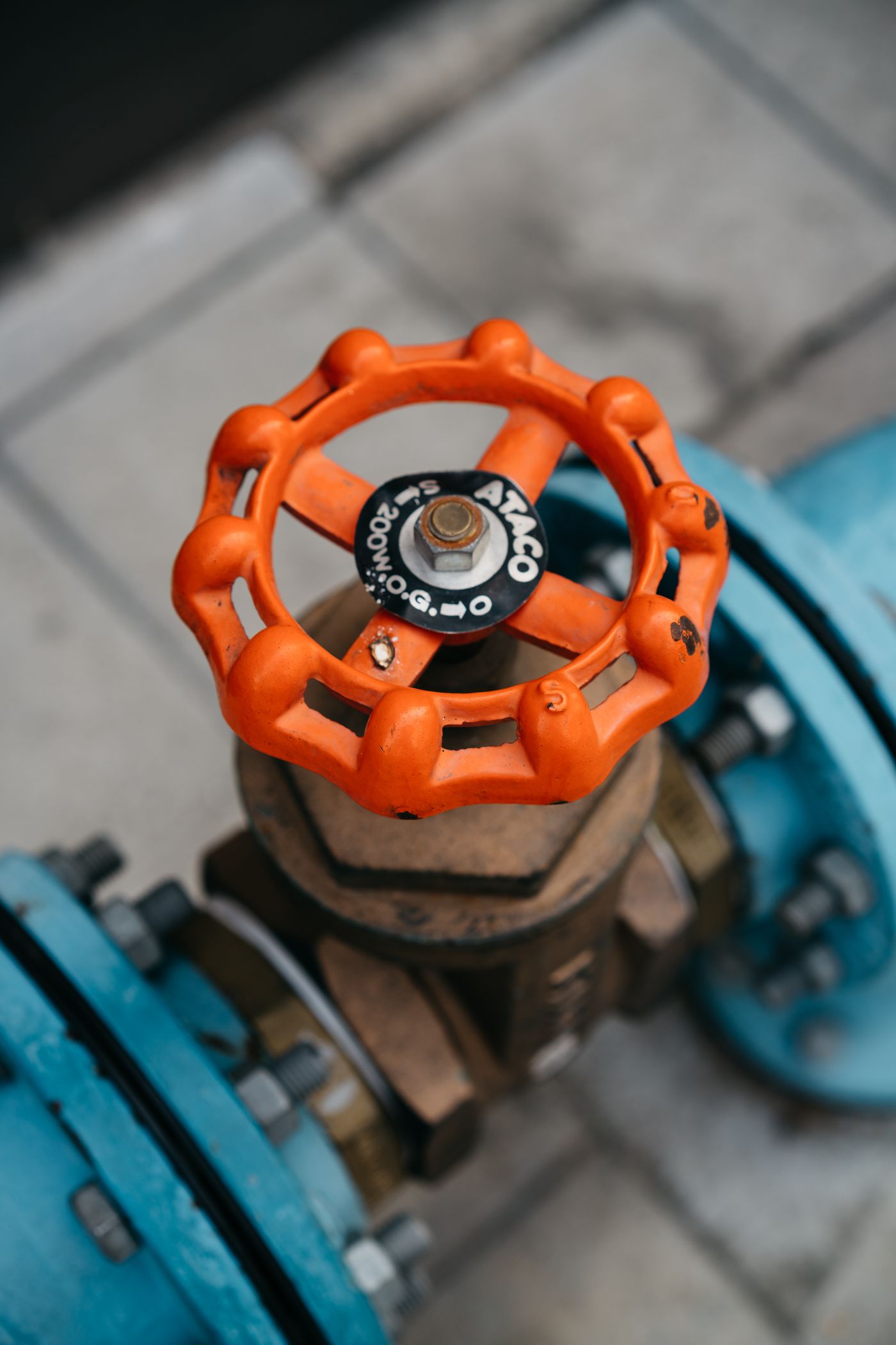 An orange valve handwheel on blue process piping